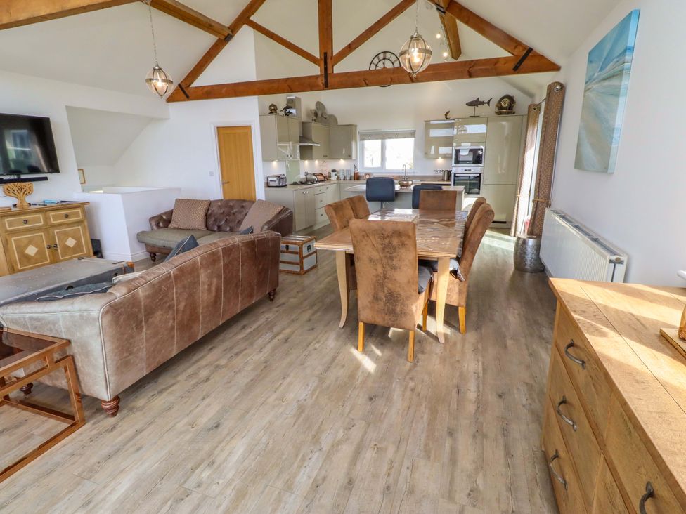 A living room with a dining table and kitchen area at Spindrifter Beadnell