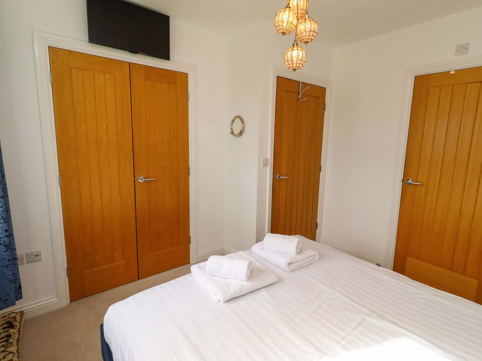 A bedroom with a bed and doors at Spindrifter in Beadnell