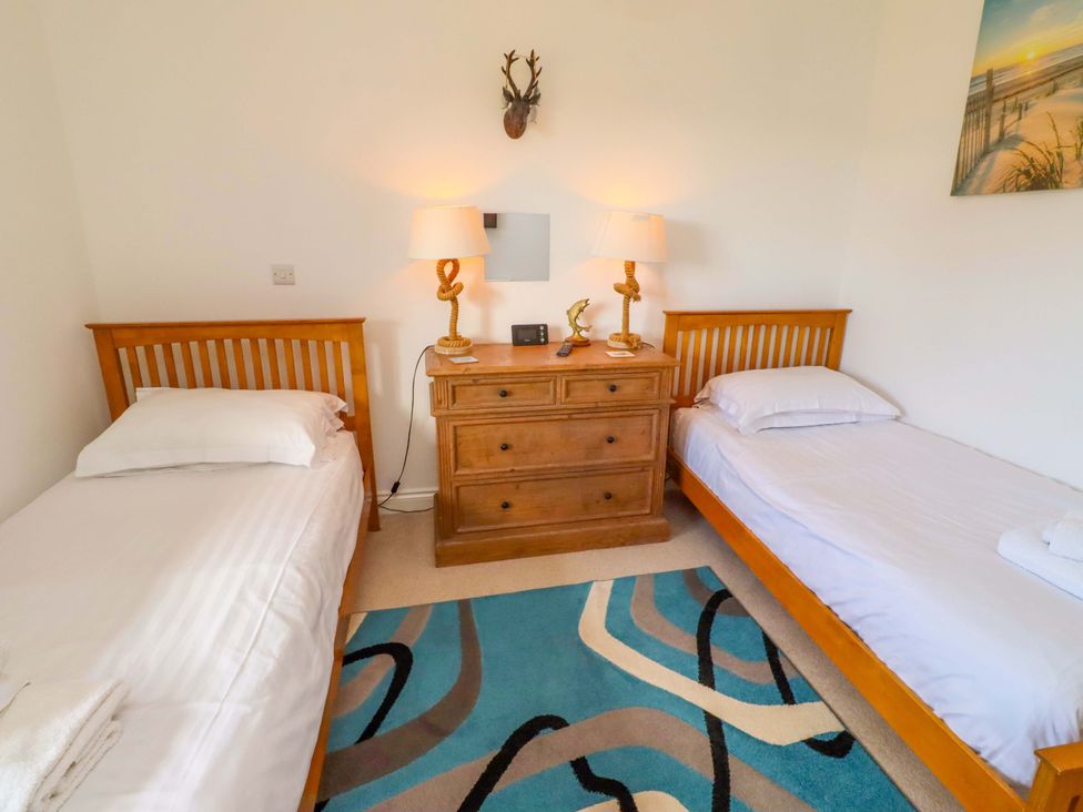 A bedroom with two beds and a dresser at Spindrifter in Beadnell