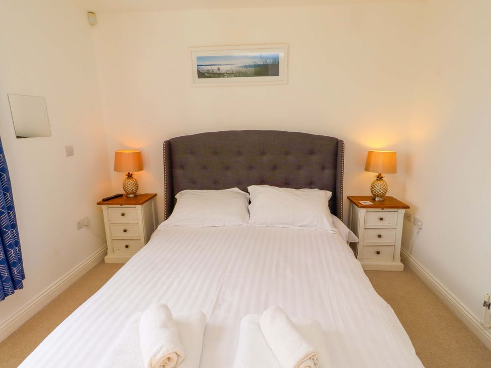 A bedroom with a bed and nightstands at Spindrifter in Beadnell