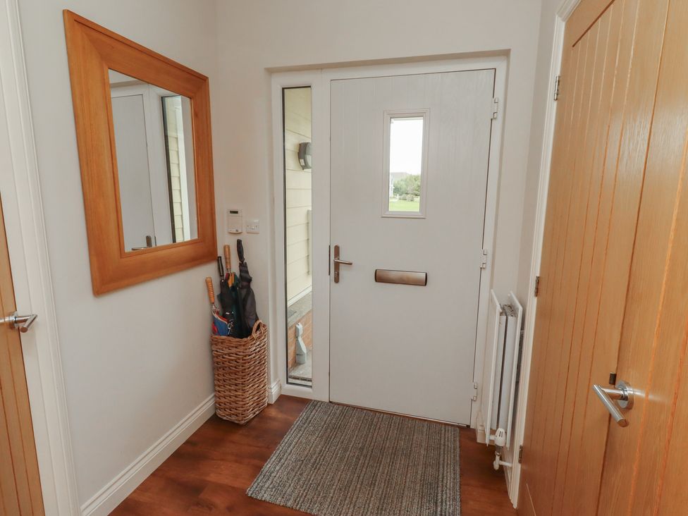 A hallway with a door and mirror at The Beach Hut in Beadnell