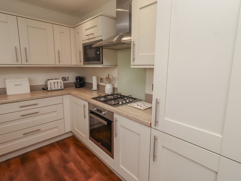 A kitchen with a gas stove and microwave at The Beach Hut in Beadnell