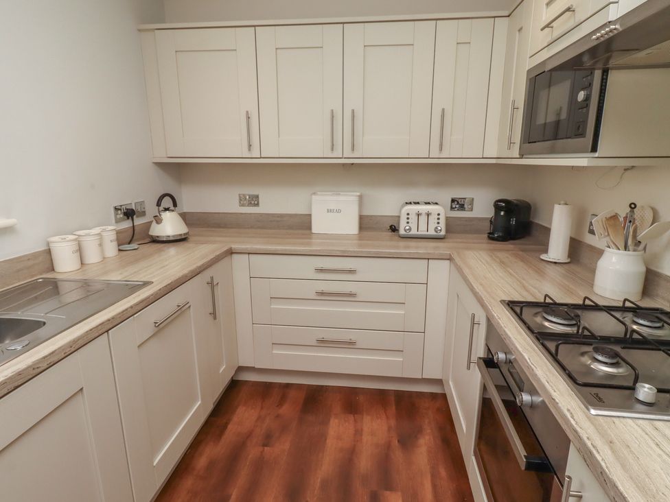 A kitchen with a sink, toaster, coffee maker and microwave at The Beach Hut in Beadnell