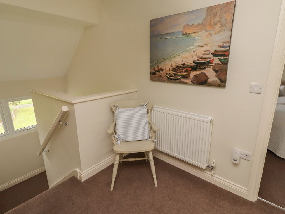 A landing area with a chair and painting at The Beach Hut in Beadnell