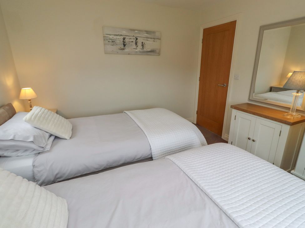 A bedroom with two single beds and a dresser at The Beach Hut in Beadnell