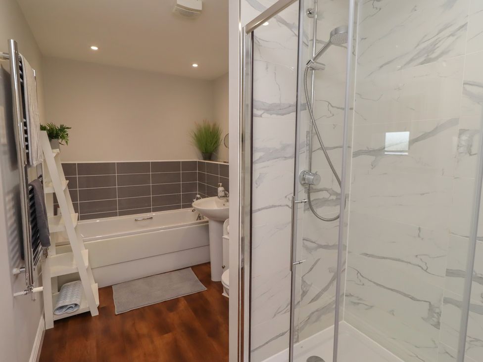 A bathroom with a shower, bathtub, sink and towels at The Beach Hut Beadnell