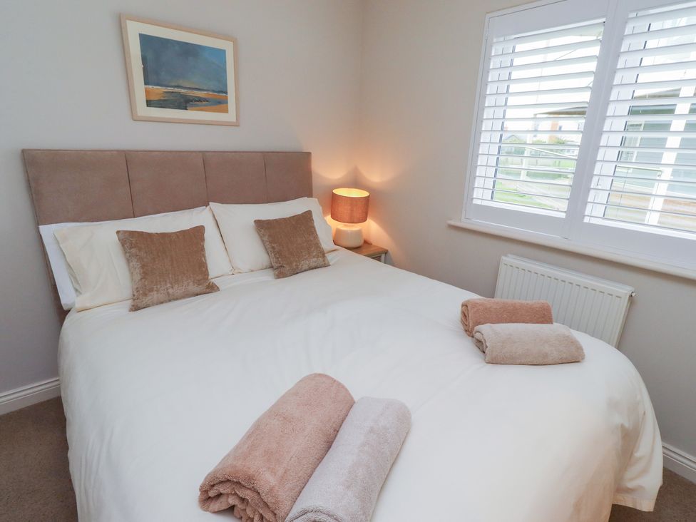 A bedroom with a bed and bedside lamp at The Beach Hut in Beadnell