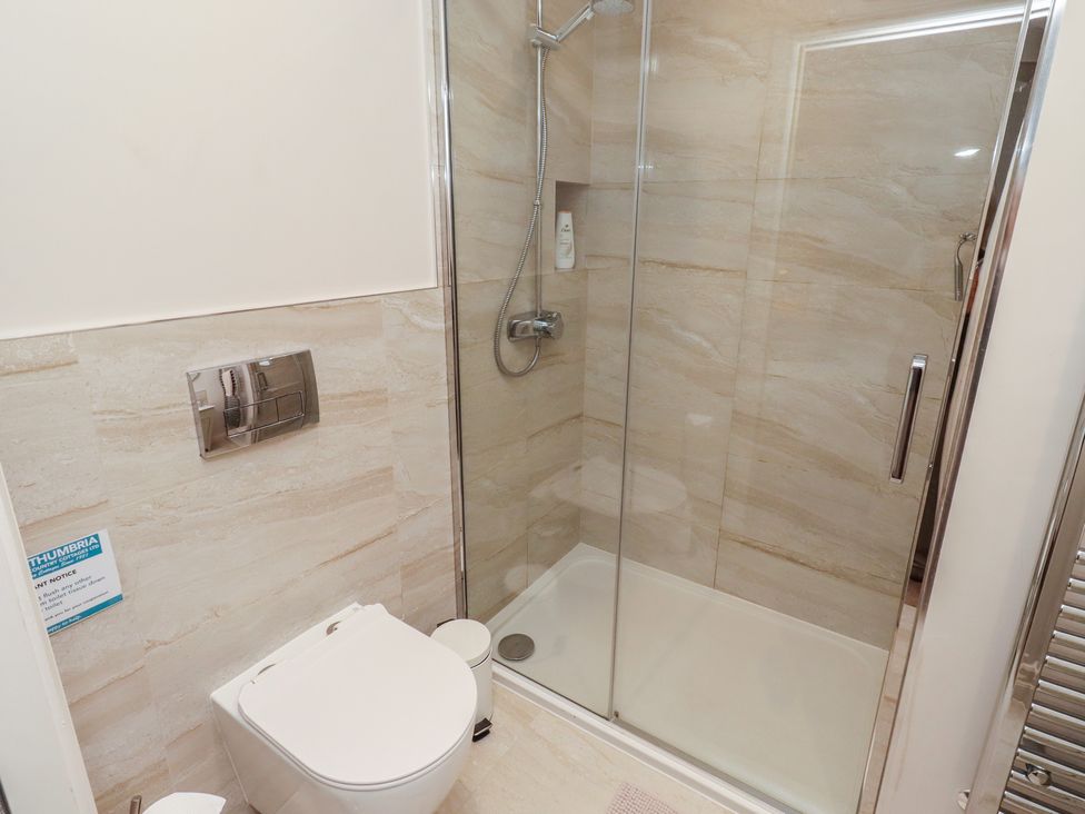 A bathroom with a shower and toilet at The Beach Hut in Beadnell
