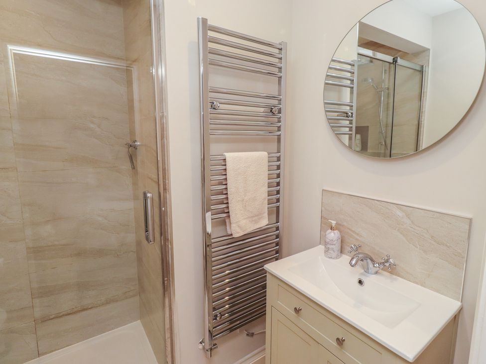 A bathroom with a shower, sink, and towel radiator at The Beach Hut in Beadnell