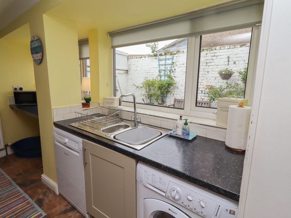 A kitchen with a sink, dishwasher, and washing machine at Number Seventeen in Amble