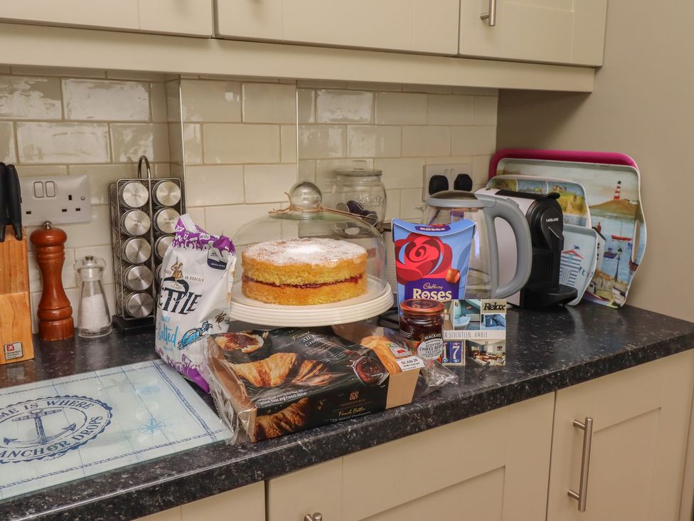 A kitchen counter with a cake, kettle, and various food items at Number Seventeen Amble