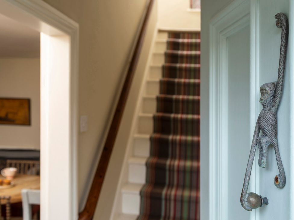 A hallway with a staircase and a decorative handle at Sandpiper (Alnmouth) in Alnmouth
