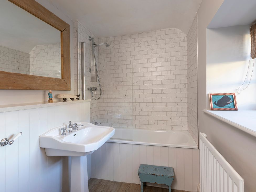A bathroom with a bathtub and sink at Sandpiper (Alnmouth)