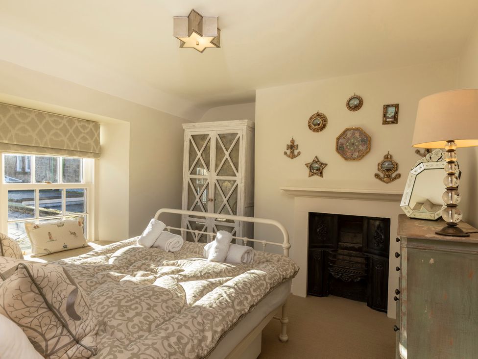 A bedroom with a bed, lamp, wardrobe, and decorative items at Sandpiper (Alnmouth)