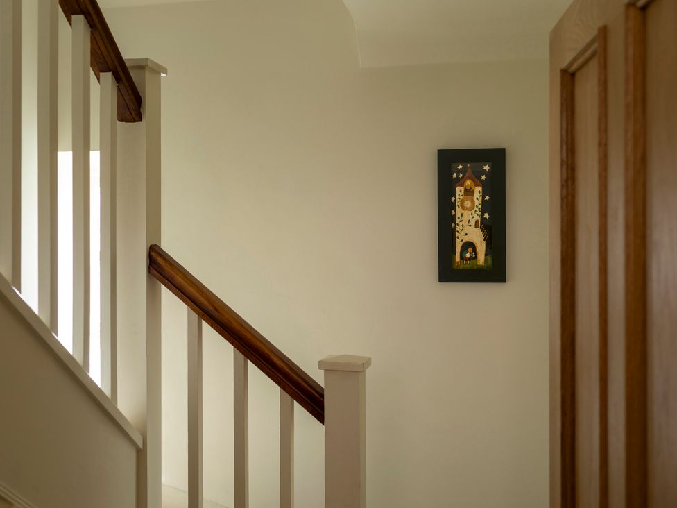 A staircase with railing and artwork on the wall at Sandpiper (Alnmouth) in Alnmouth