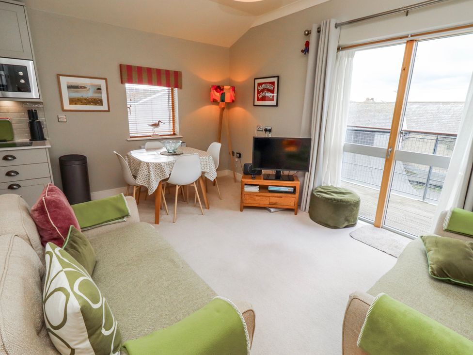A living room with a sofa, dining table, and television at Cuddy's Holm in Seahouses