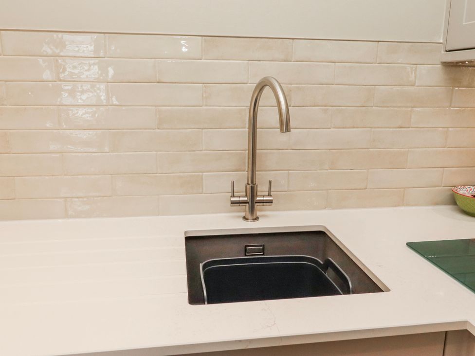 A kitchen sink with faucet and countertop at Cuddy's Holm in Seahouses