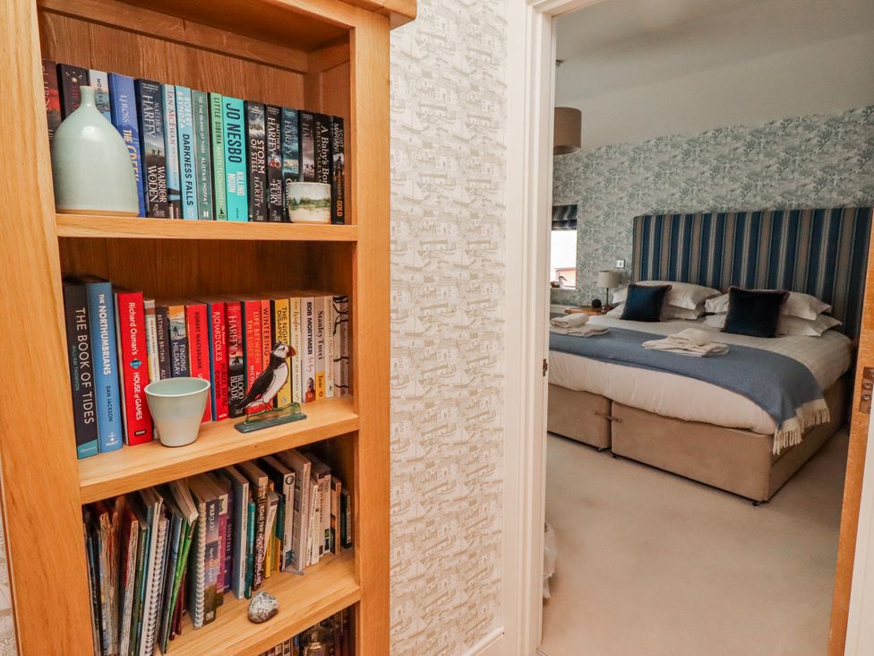 A bookshelf with books and a view of a bedroom at Cuddy's Holm Seahouses