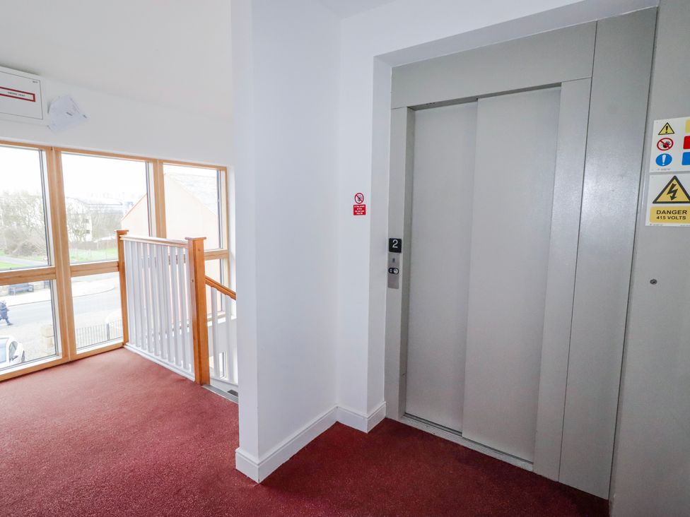 A hallway featuring an elevator and large windows at Cuddy's Holm Seahouses