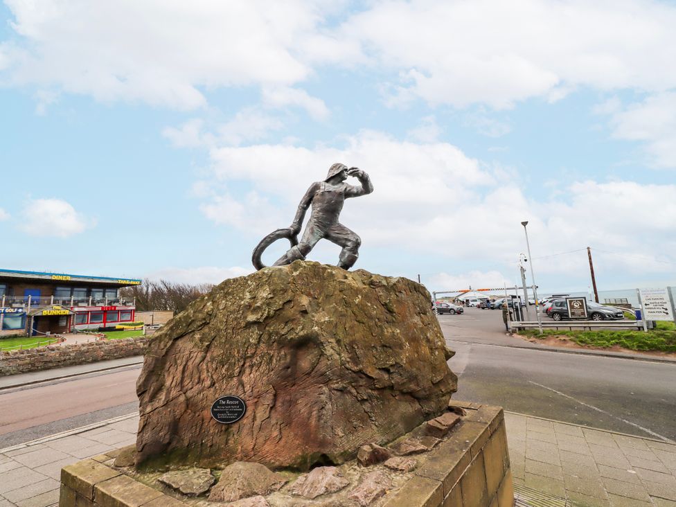 A statue on a rock near a road at Cuddy's Holm in Seahouses