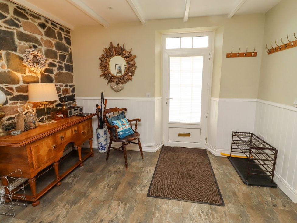 An entryway with a stone wall and a chair at Coble Cottage in Craster