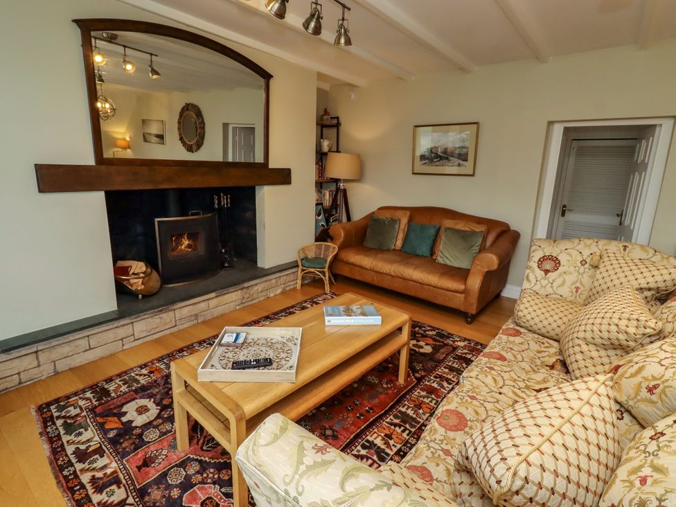 A living room with a sofa and fireplace at Coble Cottage in Craster