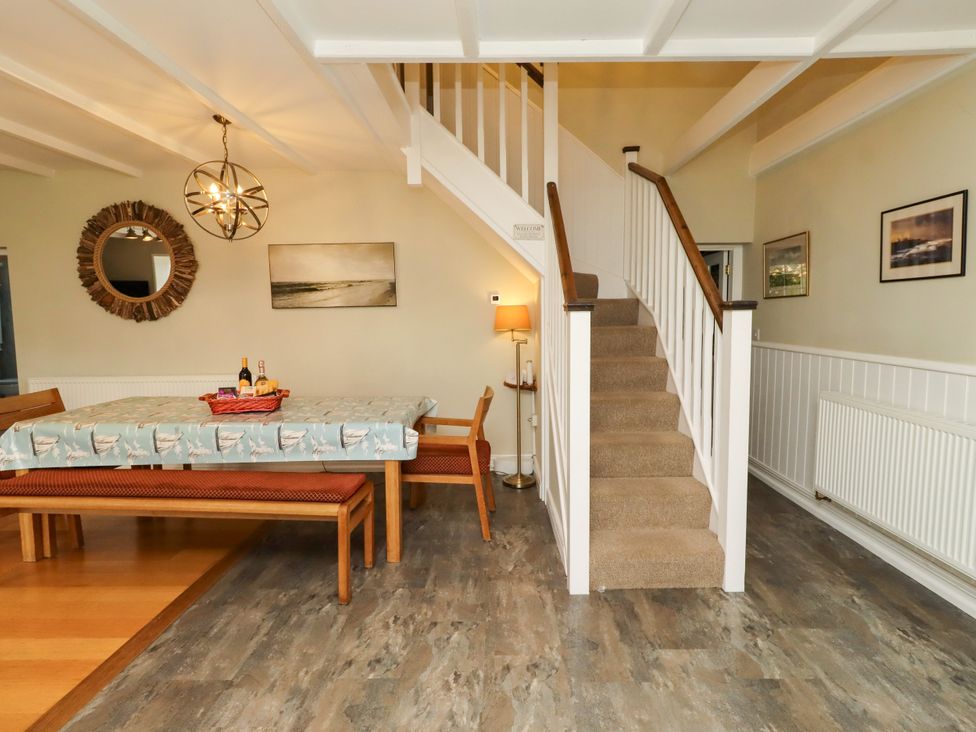 A dining room with a table and staircase at Coble Cottage Craster