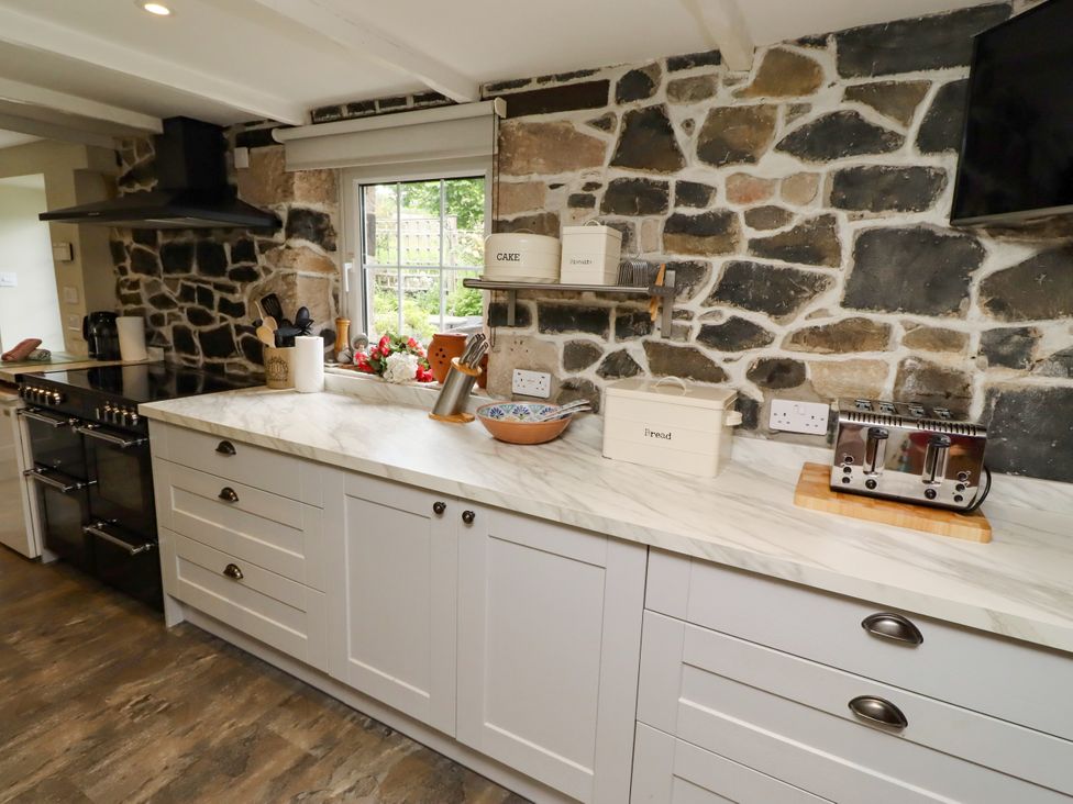 A kitchen with a stove and countertop at Coble Cottage in Craster