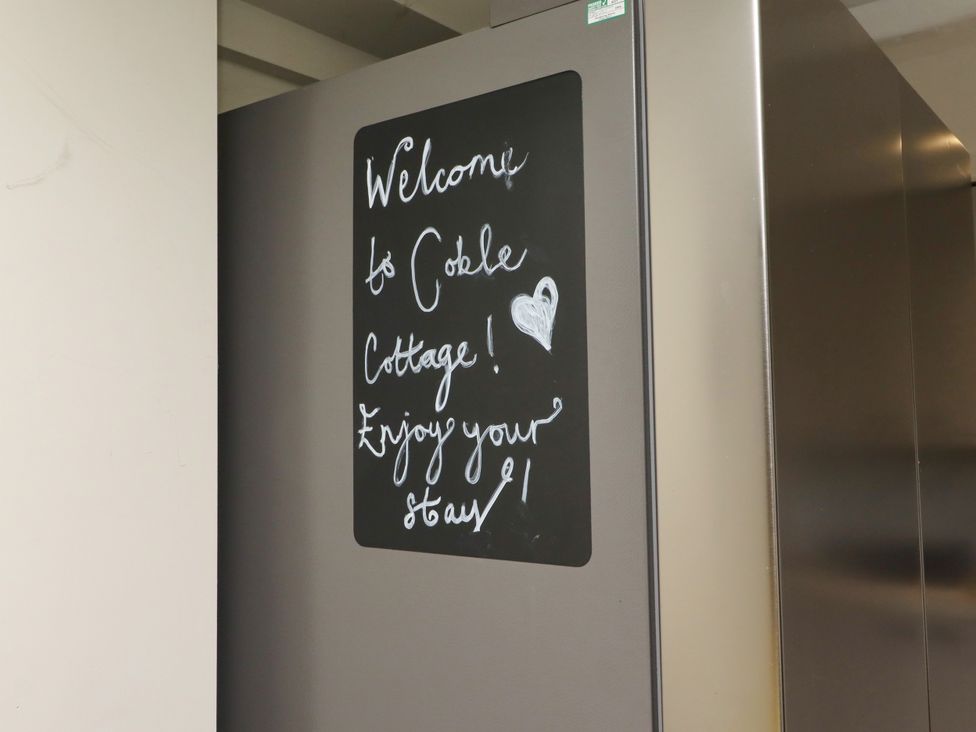 A welcome note on a chalkboard attached to a refrigerator at Coble Cottage in Craster