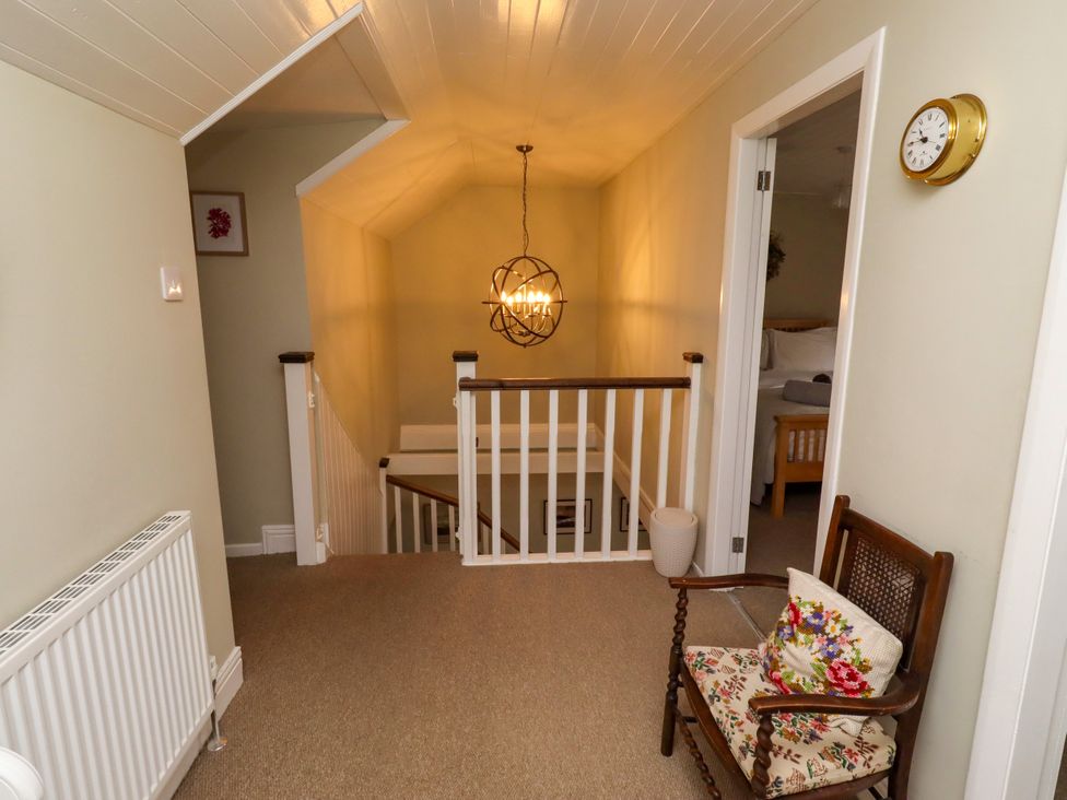 A landing with a staircase and light fixture at Coble Cottage Craster