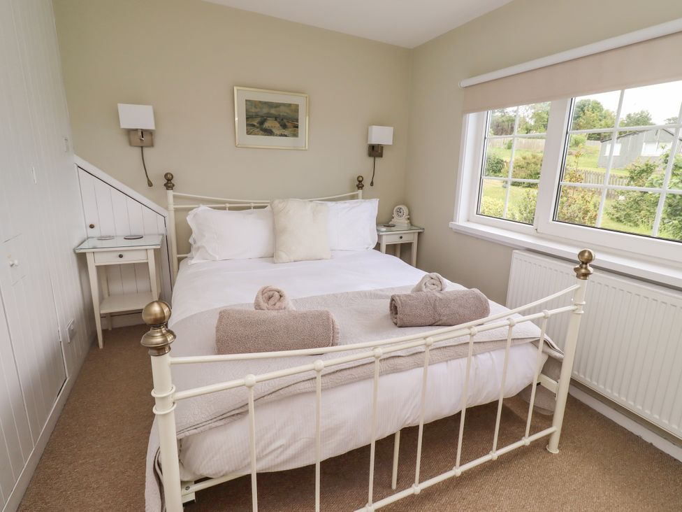 A bedroom with a double bed and nightstand at Coble Cottage in Craster