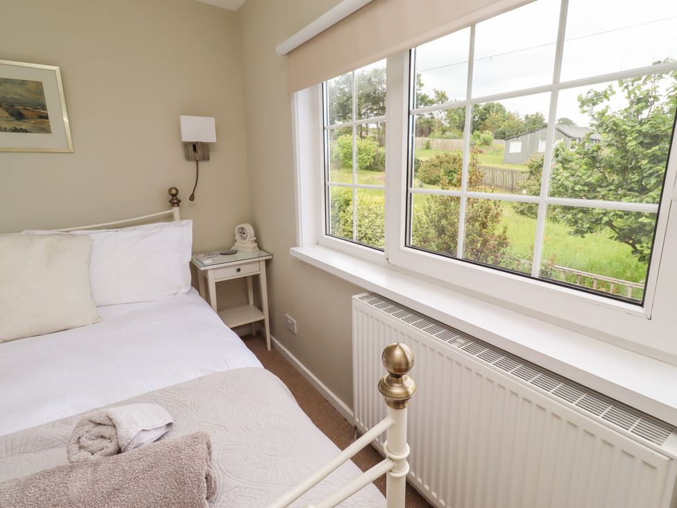A bedroom with a bed and bedside table at Coble Cottage in Craster