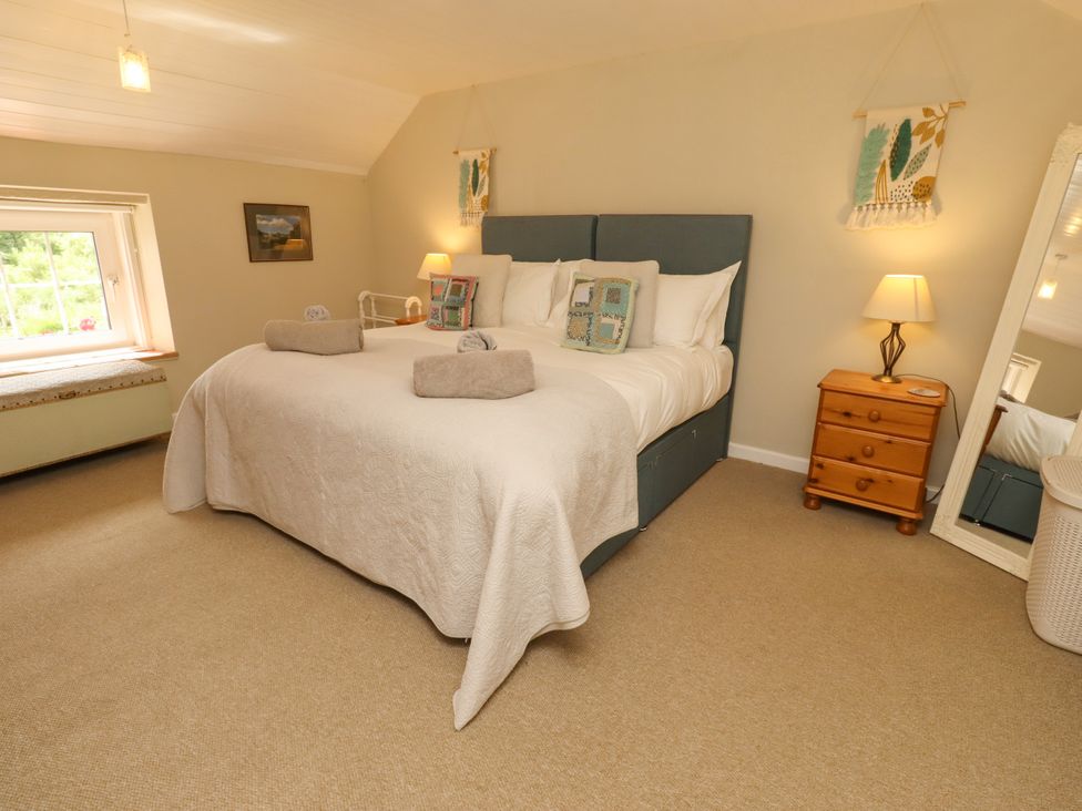 A bedroom with a large bed and bedside table at Coble Cottage Craster