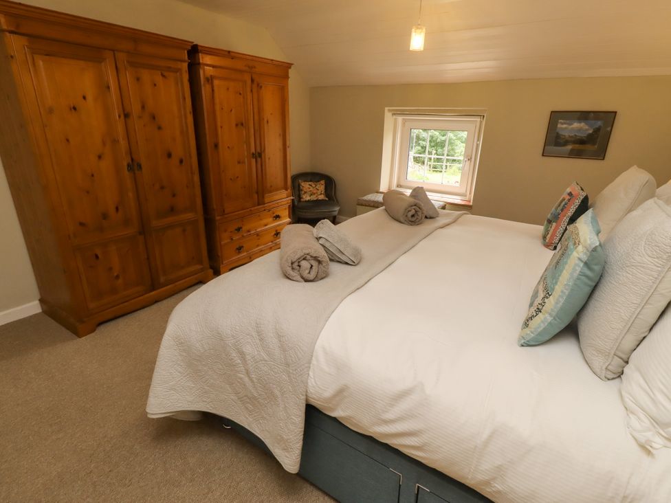 A bedroom with a bed and wardrobe at Coble Cottage Craster