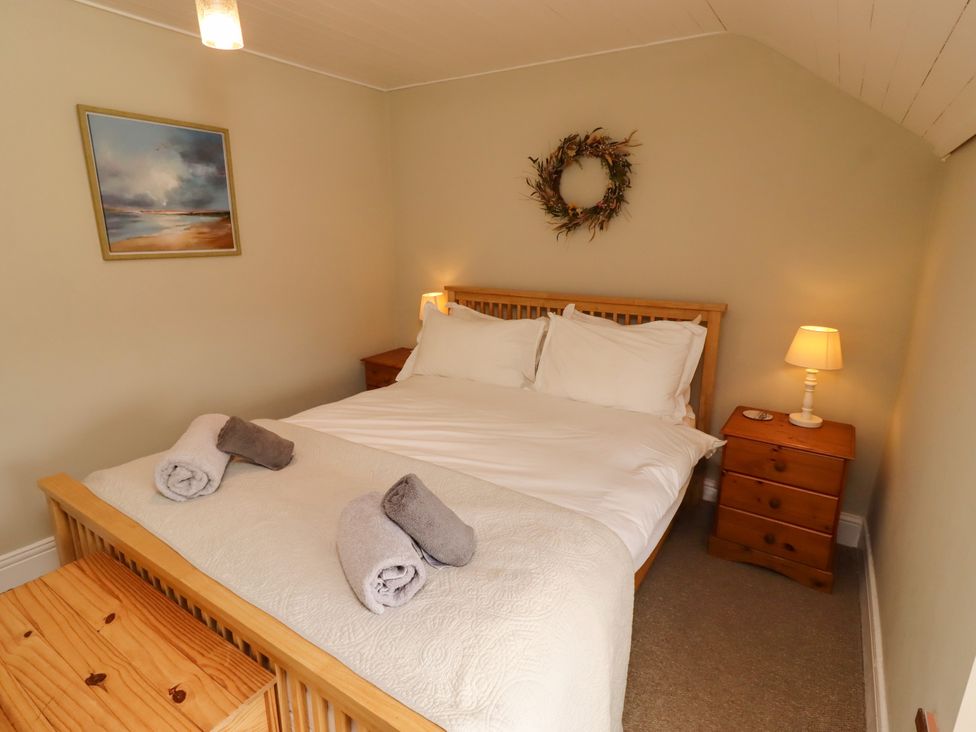 A bedroom with a bed and nightstand at Coble Cottage Craster
