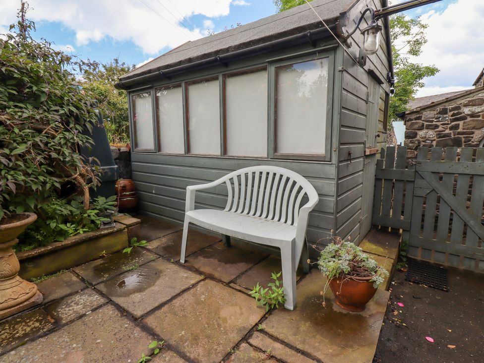 A garden with a plastic chair and a shed at Coble Cottage in Craster