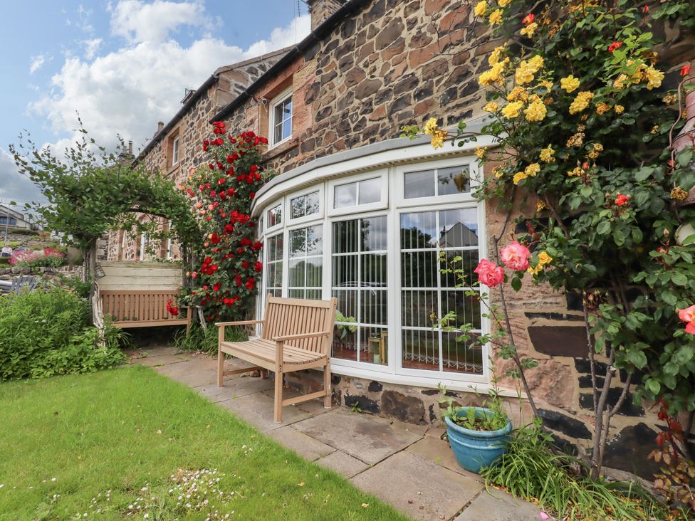 A garden with flowers and a bench at Coble Cottage in Craster