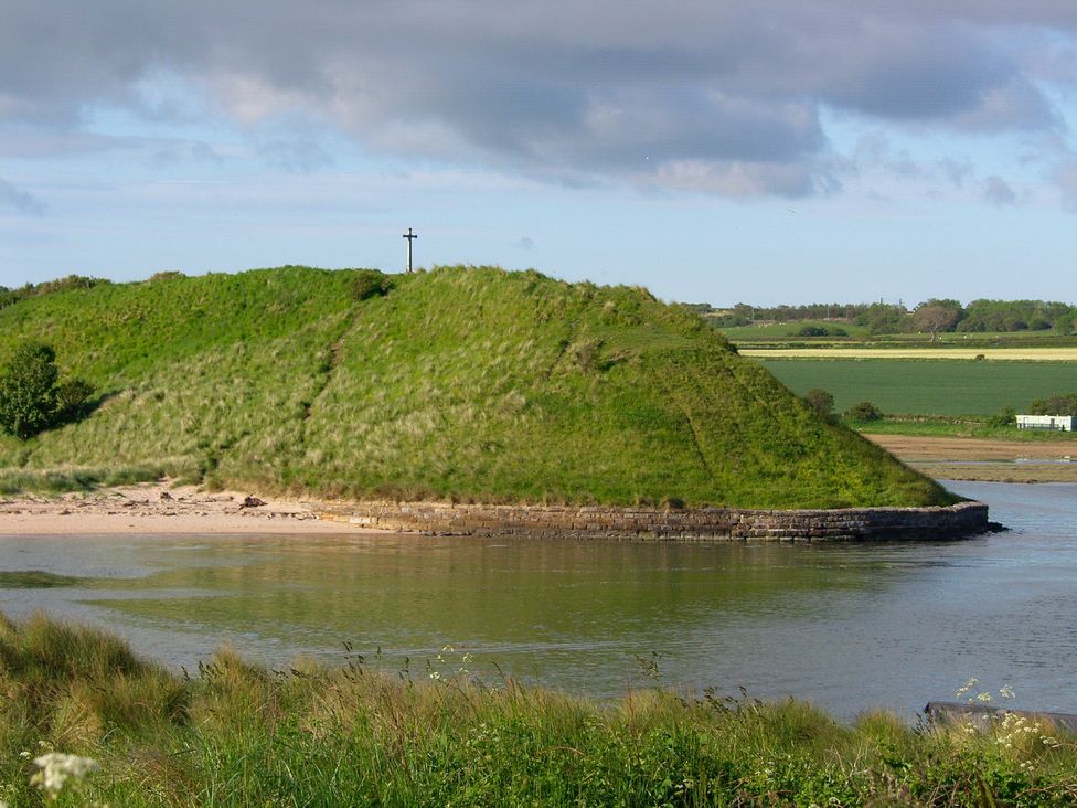 A view of a grassy hill next to water at Percy Cottages No4 Alnmouth