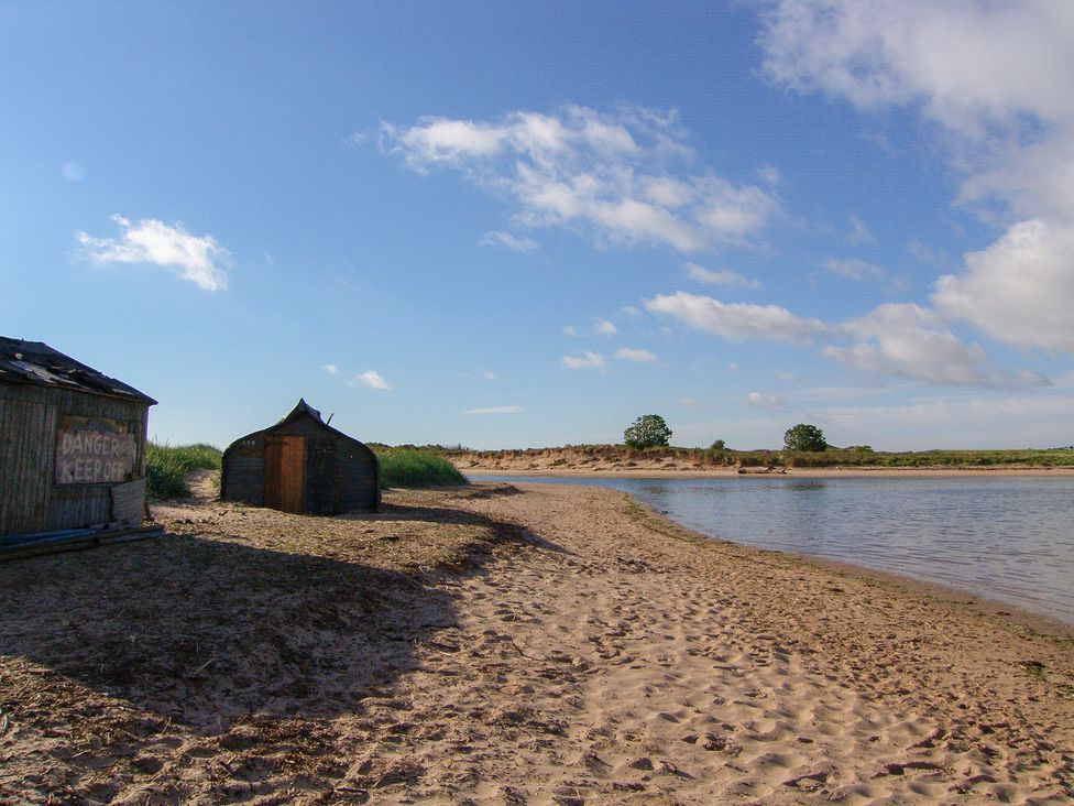 A beach scene with a shed and water at Percy Cottages No4 in Alnmouth