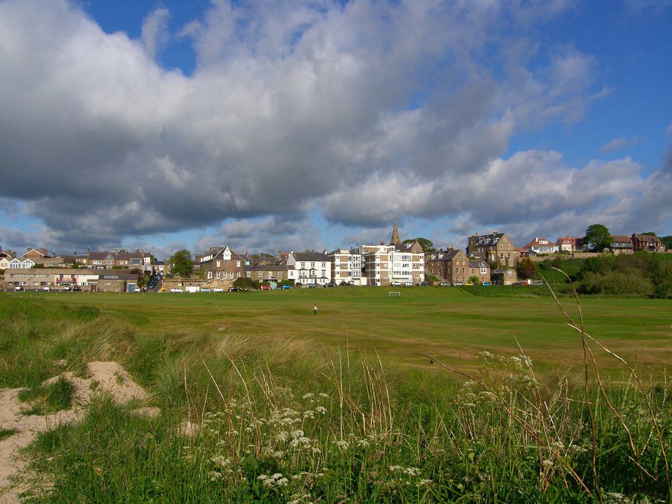 A grassy area with houses in the background at Percy Cottages No4 Alnmouth