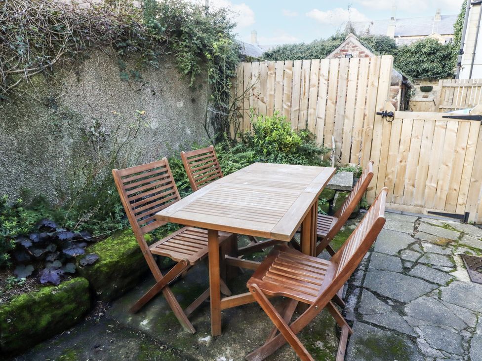 A garden with a wooden table and chairs at Percy Cottages No4 in Alnmouth