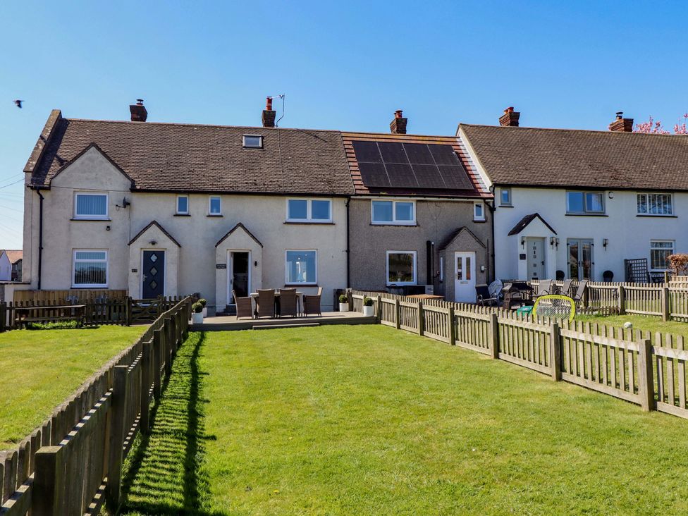 A row of houses with a garden and fences at Dunford Cottage in Bamburgh