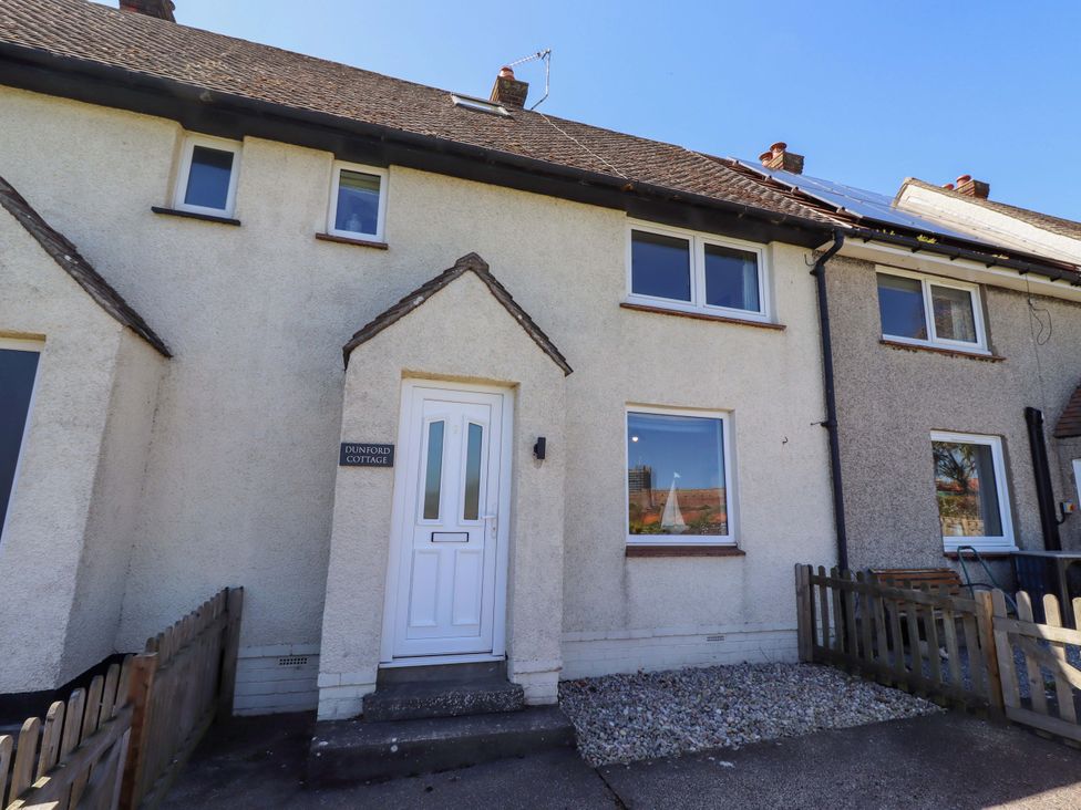A cottage with a front door and windows at Dunford Cottage in Bamburgh