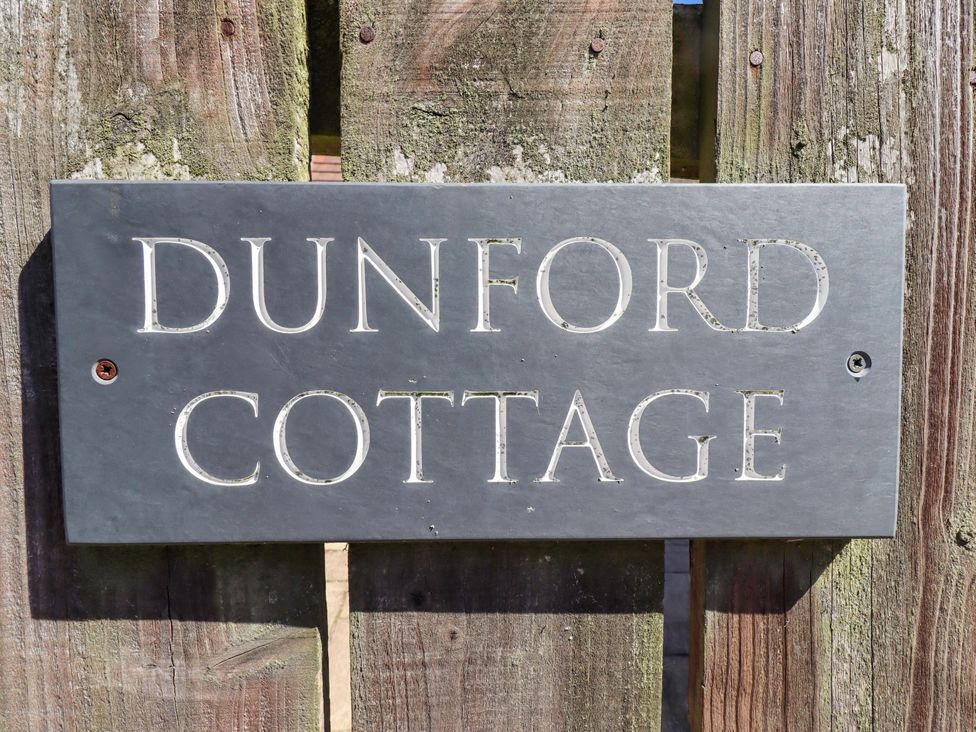 A nameplate reading Dunford Cottage on a wooden fence in Bamburgh