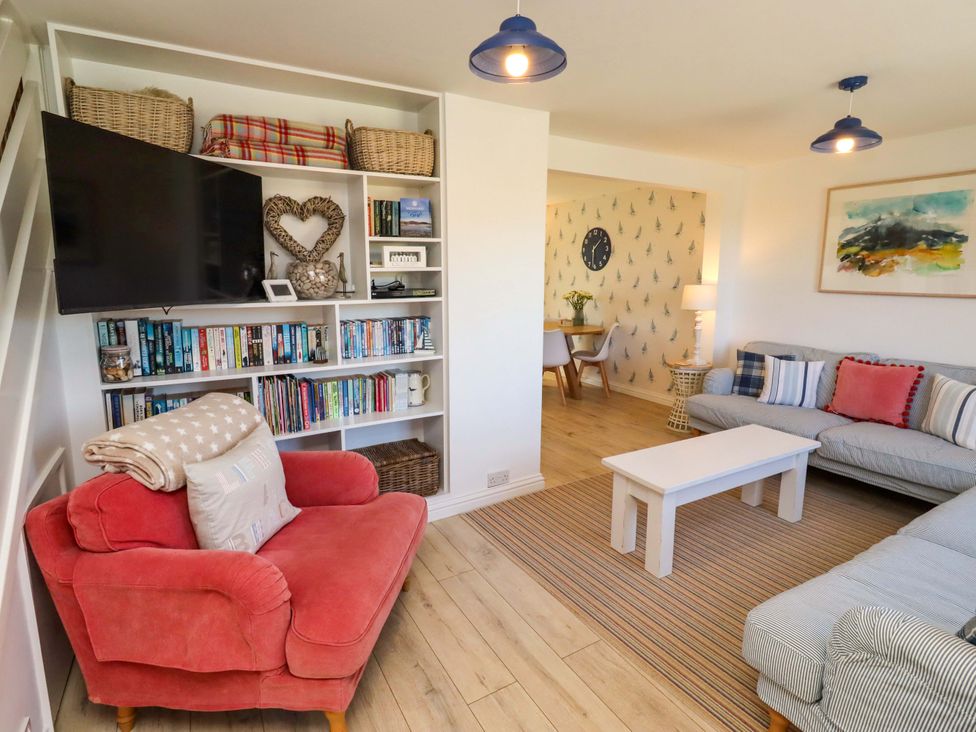 A living room with a television and bookshelves at Dunford Cottage Bamburgh