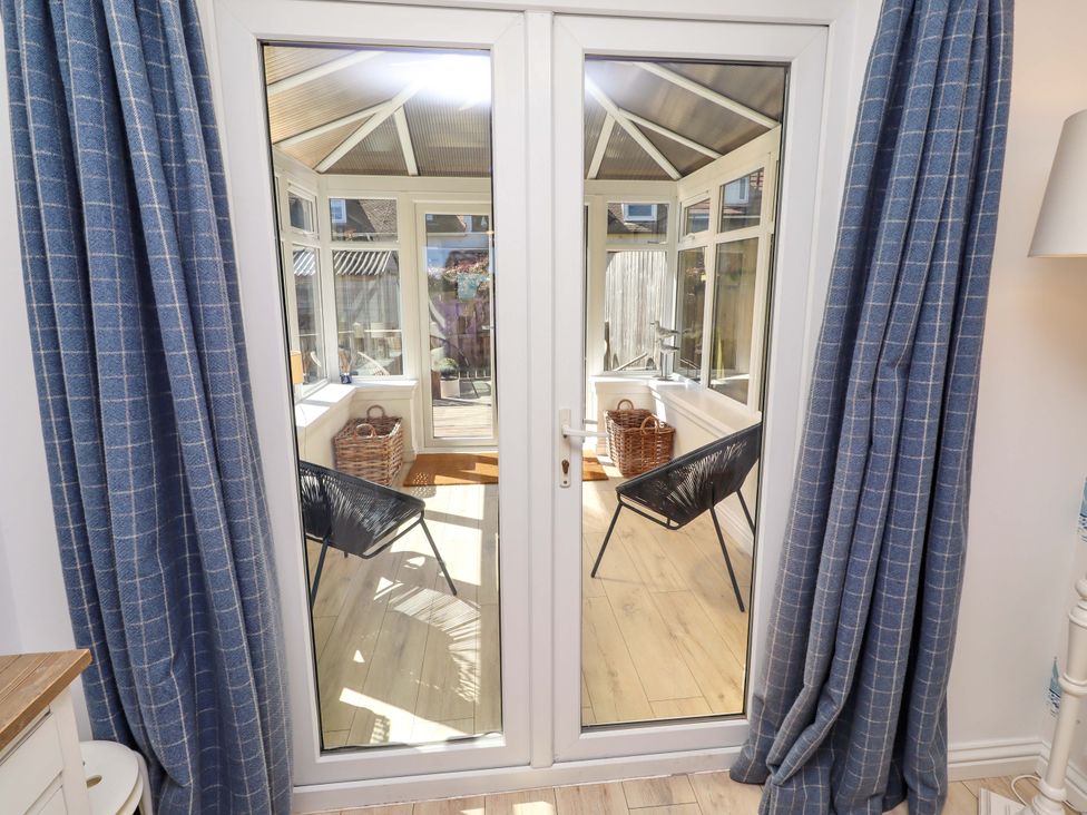 A conservatory with chairs and doors at Dunford Cottage Bamburgh