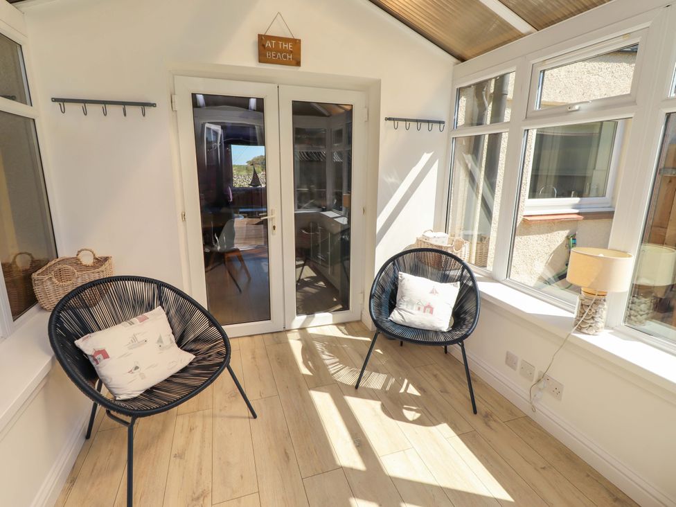 A conservatory with two chairs and a lamp at Dunford Cottage in Bamburgh