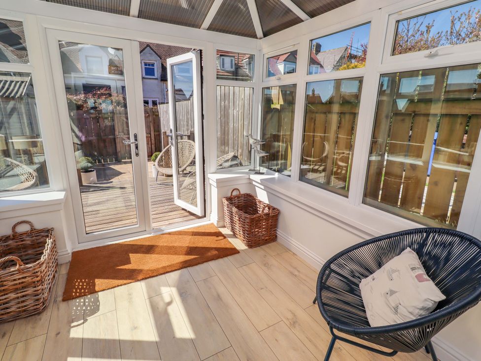 A conservatory with double doors and woven chairs at Dunford Cottage in Bamburgh