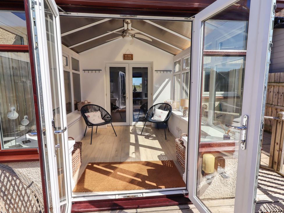 A conservatory with chairs and a table at Dunford Cottage in Bamburgh