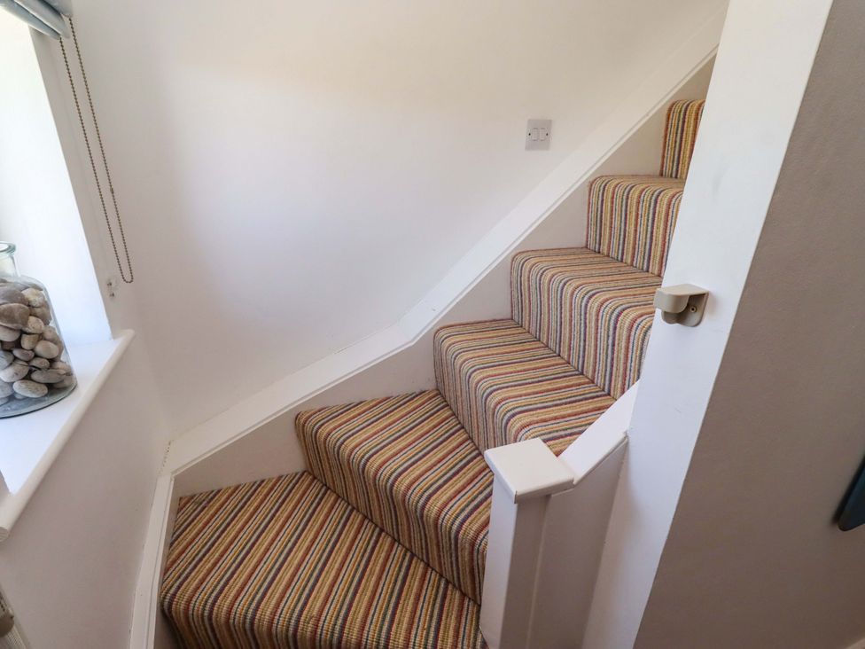 A staircase with striped carpet and window at Dunford Cottage Bamburgh